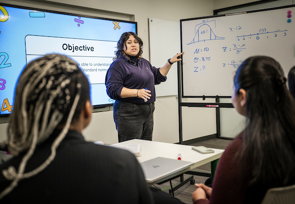 A tutor at a whiteboard explaining math concepts